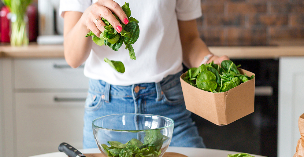 Женщина готовит салат из свежего шпината на кухне — клетчатка и зелень для здоровья кишечника и микробиоты