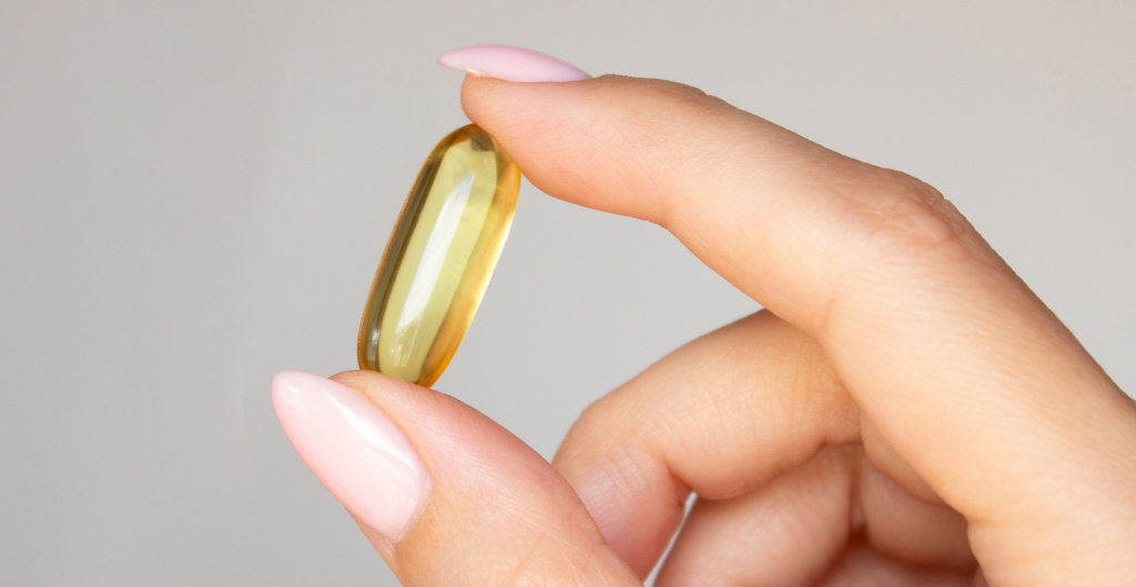 Капсула омега-3 в руке на светлом фоне, иллюстрация темы нутриентов и женского здоровья