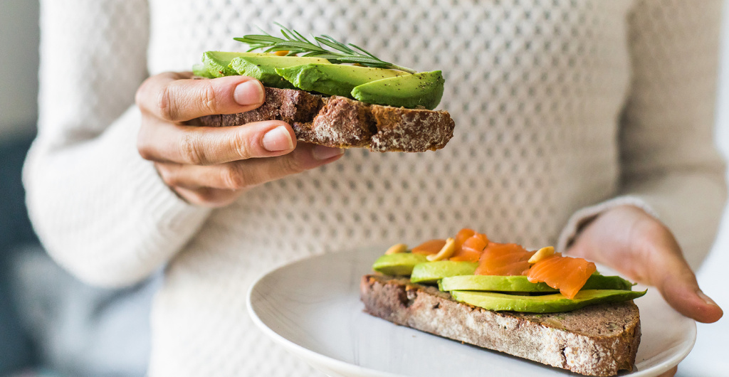 Тост с авокадо и ломтиками рыбы на тарелке, пример продуктов с полезными жирами для рациона